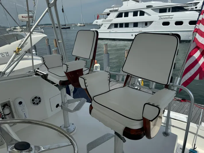Negotiator Yacht Photos Pics 1994 Hatteras 54 Convertible yacht helm with white cushioned chairs, docked near other boats.