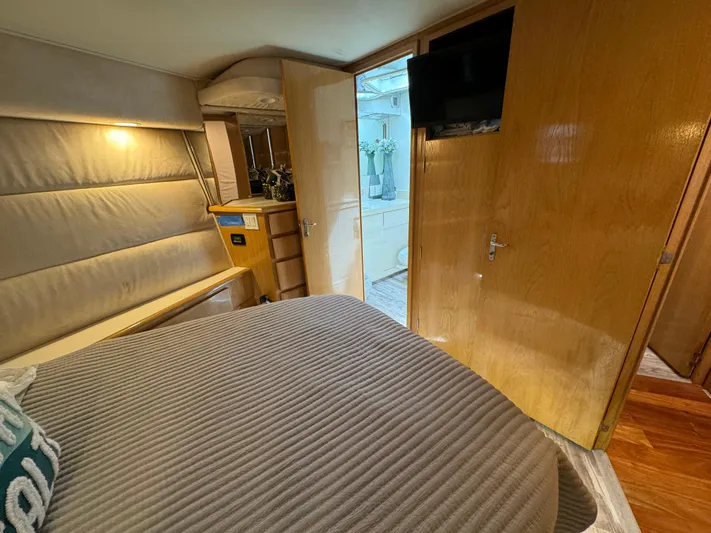 Negotiator Yacht Photos Pics 1994 Hatteras 54 Convertible yacht bedroom with cozy bed, TV, and wooden interior.