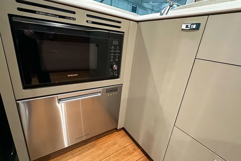 F45021 Yacht Photos Pics Modern kitchen appliances in a 2021 Princess F45 yacht, featuring Samsung microwave and Fisher & Paykel dishwasher.