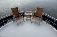 Two wooden chairs and a table on a 2005 Custom Knight Craft 12,50 boat deck.