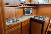 Wooden yacht kitchen with sink, microwave, stove, and cabinets; Custom Knight Craft 12,50, 2005 model.