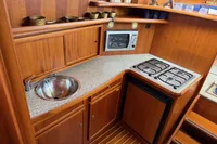Compact wooden yacht kitchen with sink, stove, and microwave; Custom Knight Craft 12,50, 2005 model.