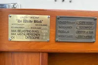 Plaques on a wooden surface displaying boat specifications and details, including weight and capacity.