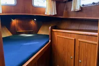 Cozy cabin interior of 2005 Custom Knight Craft 12,50 with wood paneling and blue bedding.