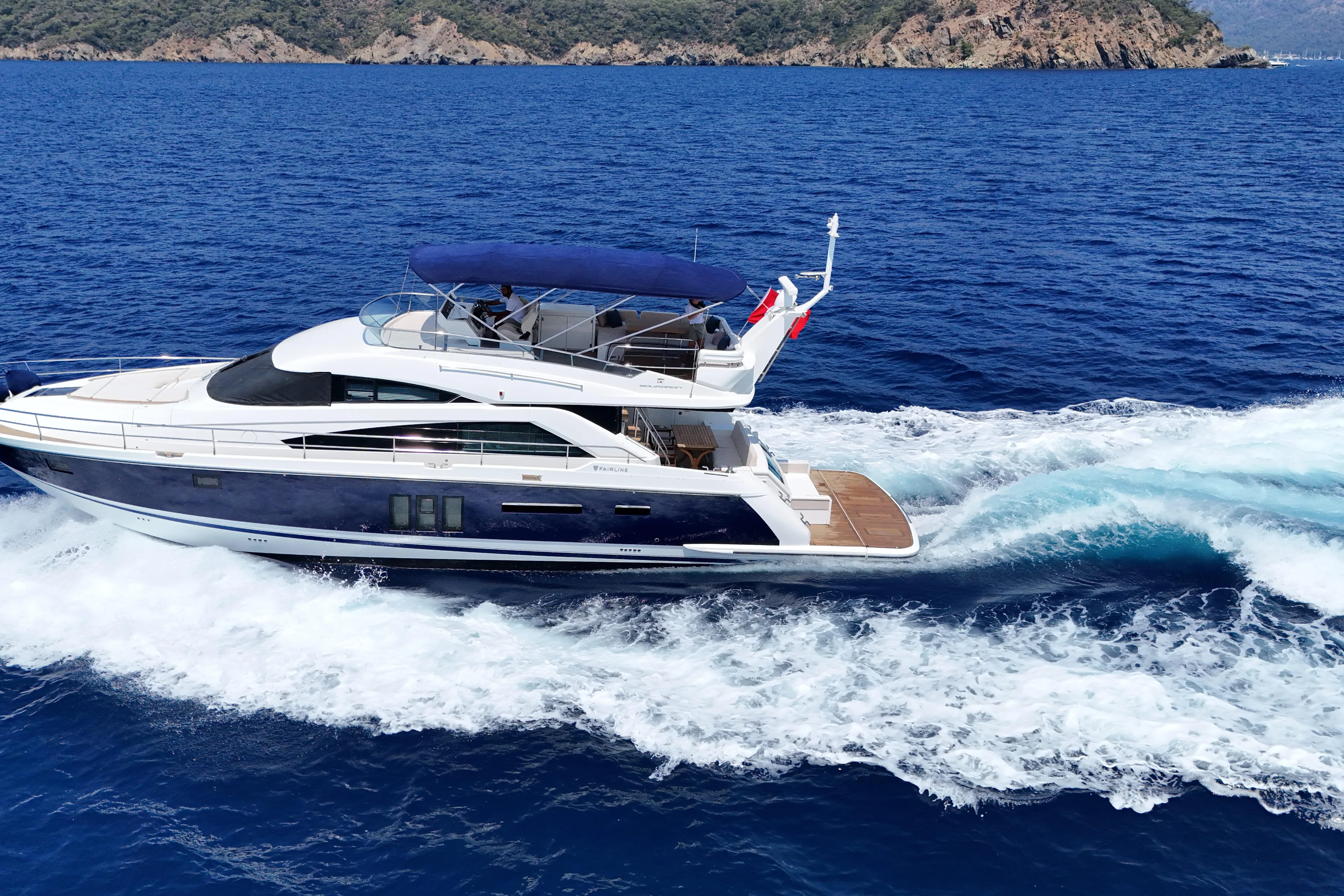  Yacht Photos Pics Luxury 2013 Fairlane Squadron yacht cruising on blue ocean near rocky coastline.