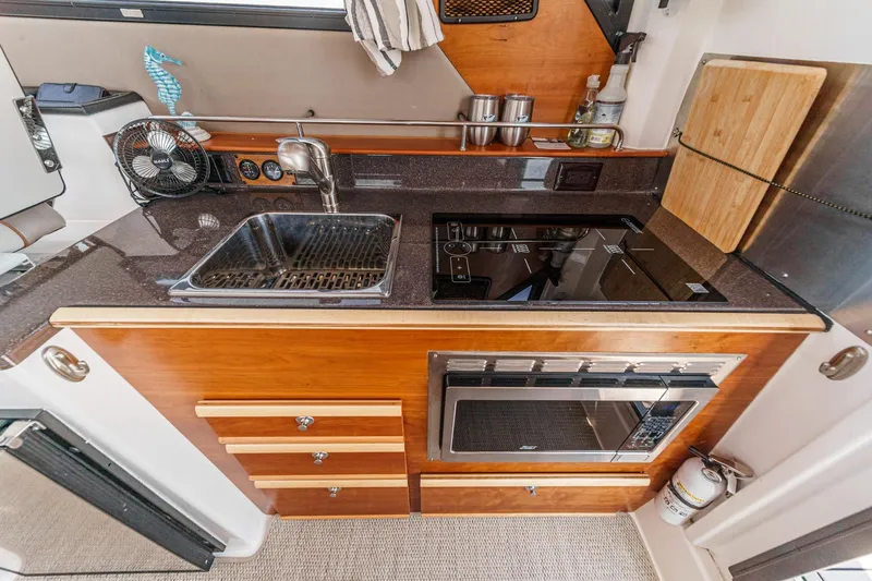 Sea Horse Yacht Photos Pics 2023 Cutwater 288 Coupe LE kitchen with sink, stove, and microwave in compact design.