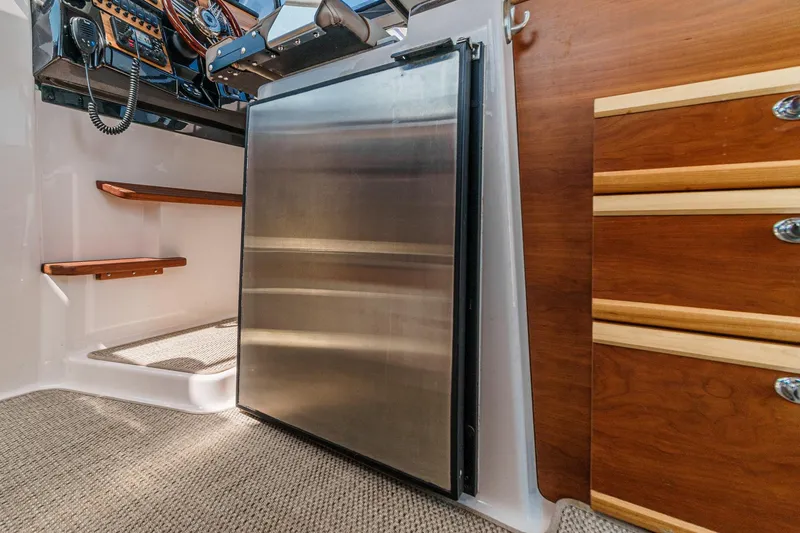 Sea Horse Yacht Photos Pics 2023 Cutwater 288 Coupe LE interior with stainless steel fridge and wooden cabinetry.