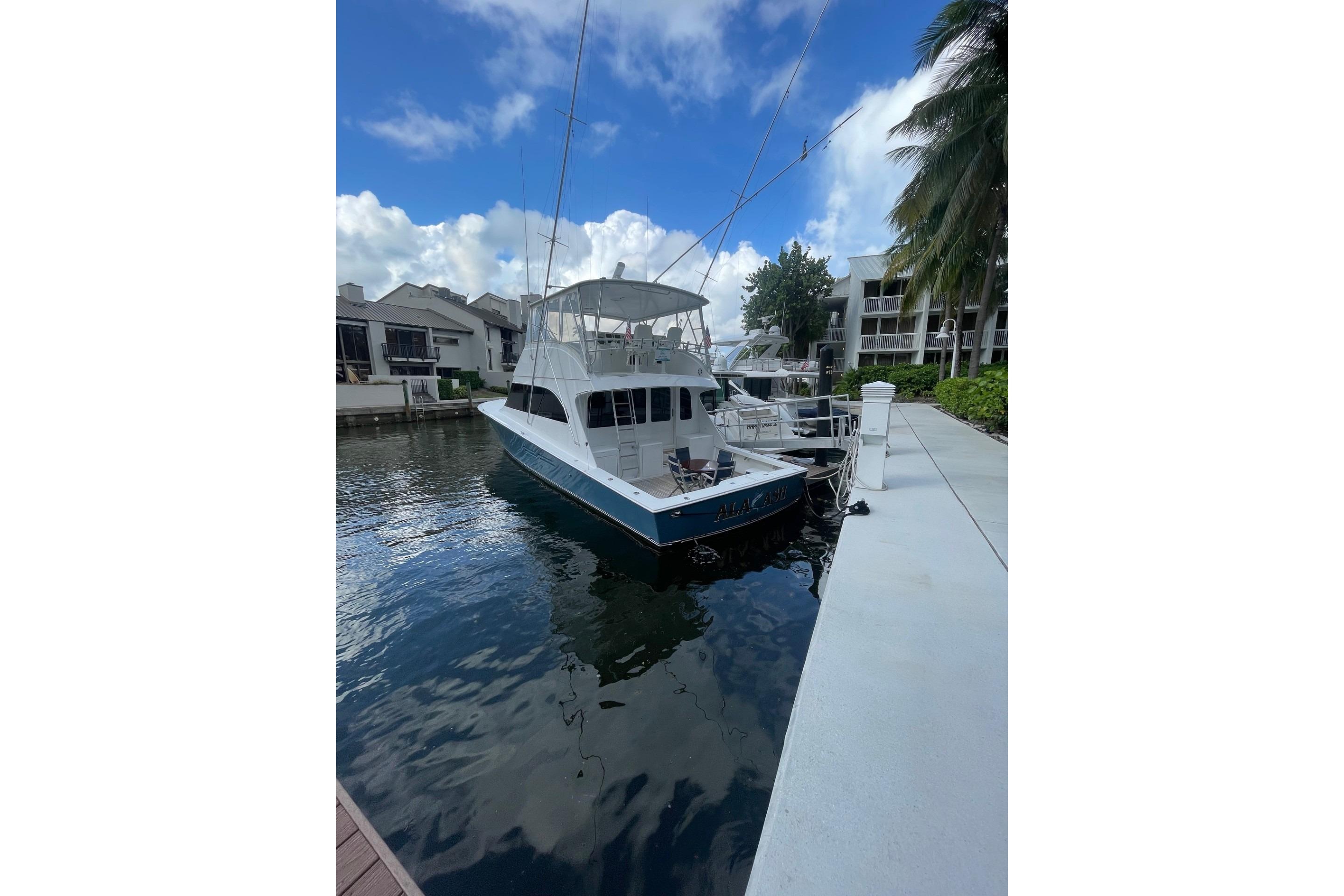 2003 Post Flybridge Convertible yacht docked at marina under blue sky.