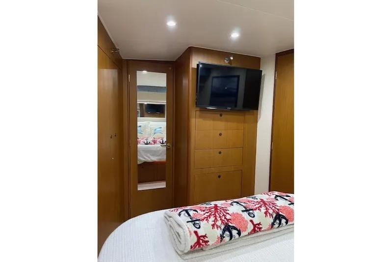 Ala-ash Yacht Photos Pics 2003 Post Flybridge Convertible cabin with TV, wooden cabinets, and decorative bedding.