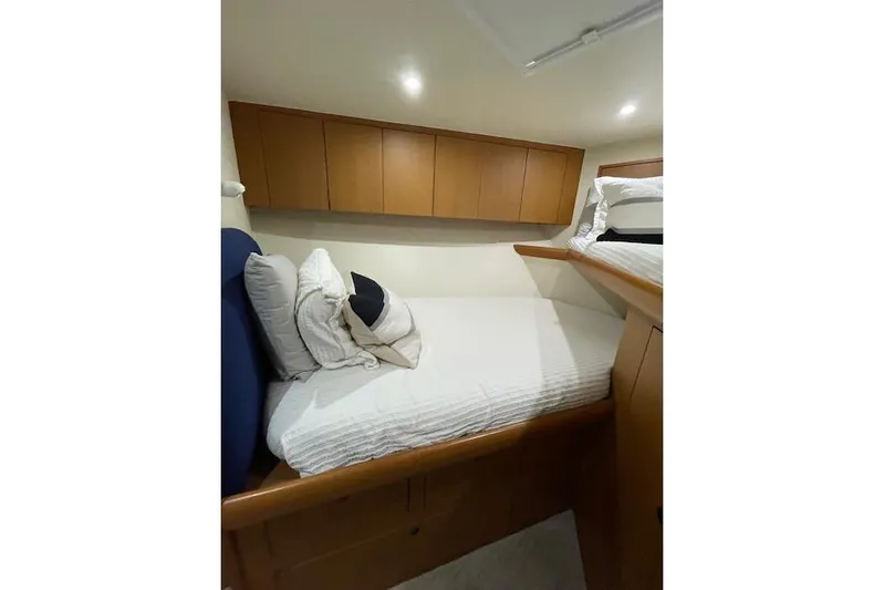 Ala-ash Yacht Photos Pics 2003 Post Flybridge Convertible cabin with cozy bed and wooden storage cabinets.