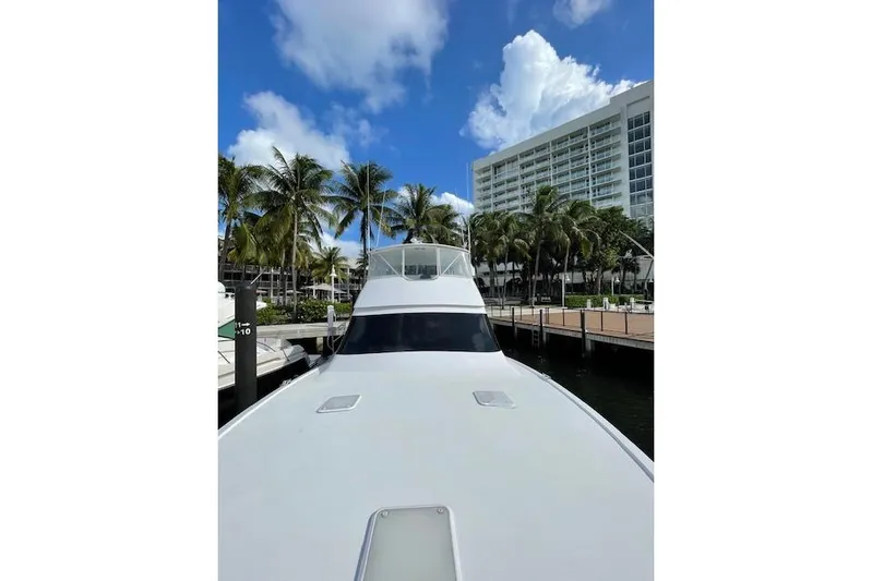 Ala-ash Yacht Photos Pics 2003 Post Flybridge Convertible yacht docked near palm trees and a modern building.
