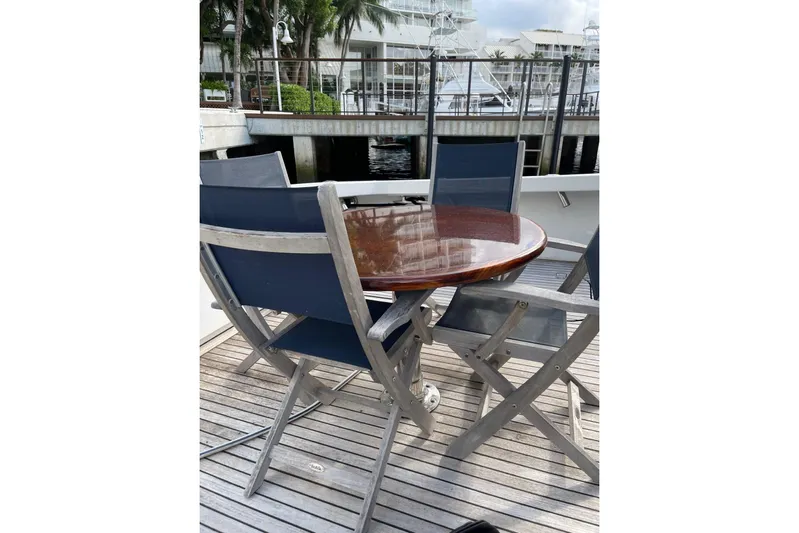 Ala-ash Yacht Photos Pics Outdoor seating on 2003 Post Flybridge Convertible yacht, featuring wooden deck and round table.