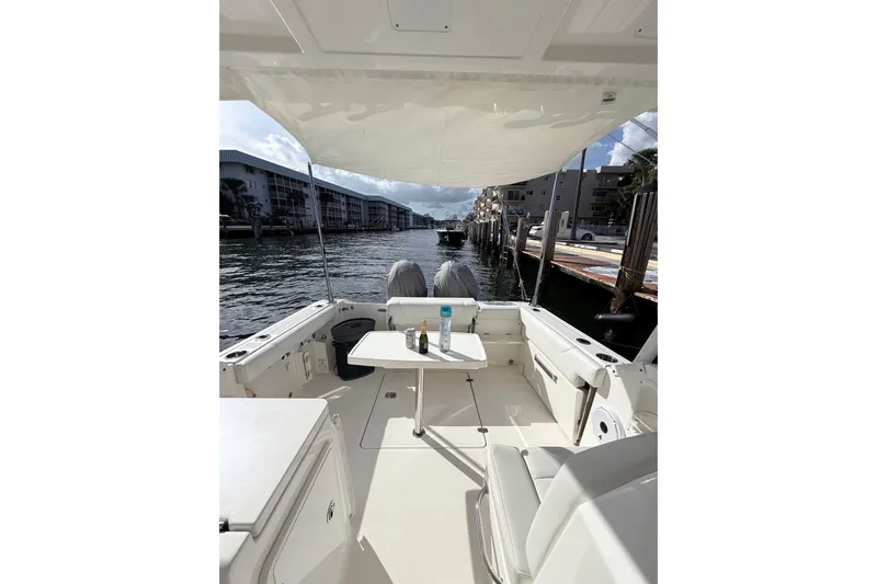  Yacht Photos Pics 2022 Pursuit DC 266 Dual Console boat interior with table, docked by waterfront buildings.