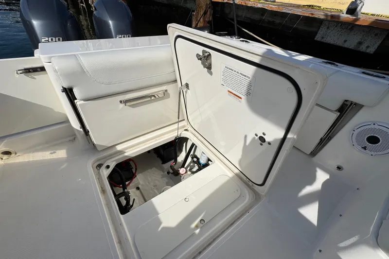  Yacht Photos Pics 2022 Pursuit DC 266 Dual Console boat with open storage compartment and visible engine components.
