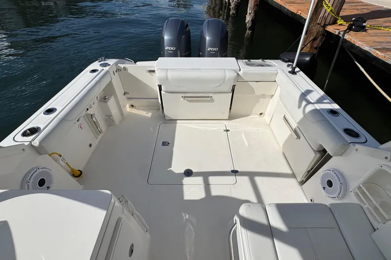  Yacht Photos Pics 2022 Pursuit DC 266 Dual Console boat interior with twin engines, docked by wooden pier.
