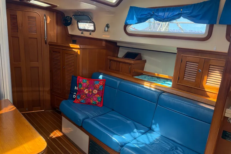 Make Me Laugh Again Yacht Photos Pics Interior of 2005 Island Packet 445 yacht with blue seating and wooden cabinetry.