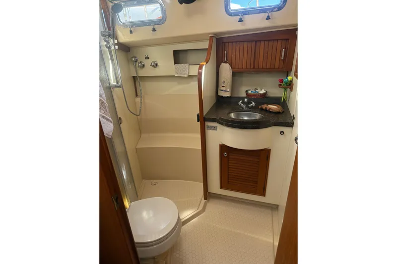 Make Me Laugh Again Yacht Photos Pics Luxurious 2005 Island Packet 445 yacht bathroom with shower, sink, and wooden cabinetry.