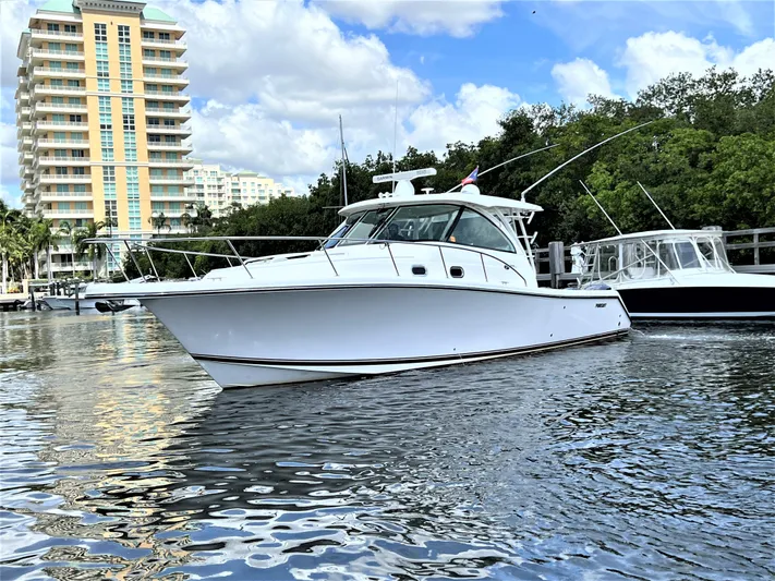 Snot Easy Yacht Photos Pics 2016 Pursuit OS 385 Offshore boat docked near high-rise buildings.