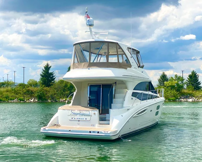 Lucid Dreams Yacht Photos Pics 2014 Meridian 441 Sedan yacht cruising on a serene lake under a cloudy sky.