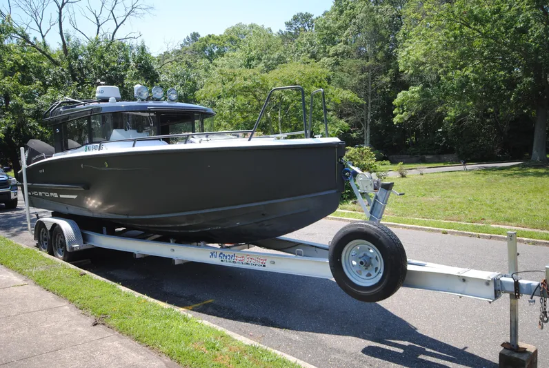  Yacht Photos Pics 2015 XO Boats 270 RS on trailer, parked outdoors with lush greenery.