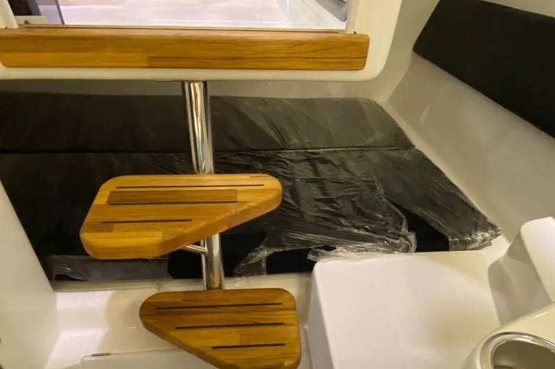  Yacht Photos Pics Interior of 2025 Hanover 305 boat with wooden steps and cushioned seating.