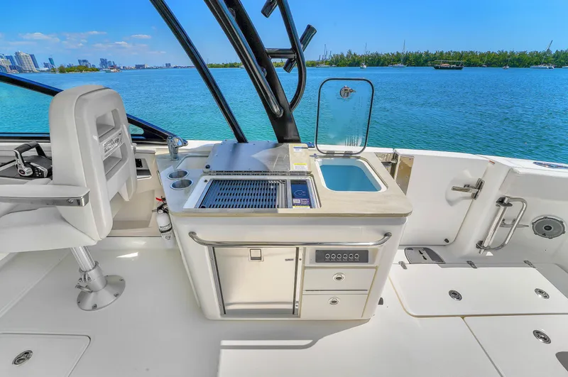  Yacht Photos Pics 2024 Boston Whaler 325 Vantage boat interior with sink and grill, overlooking blue water.