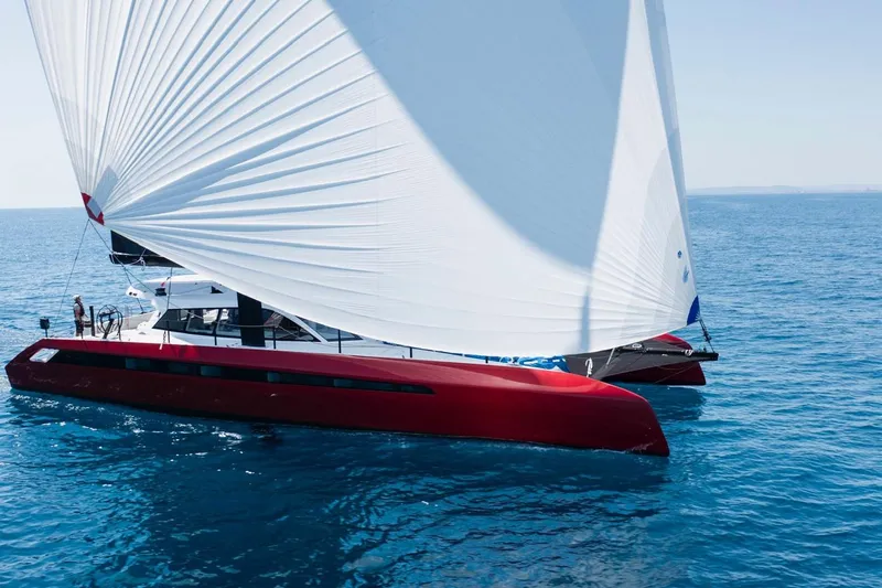 Highland Fling 18 Yacht Photos Pics 2023 Gunboat 80 sailing catamaran with red hull and white sails on open sea.