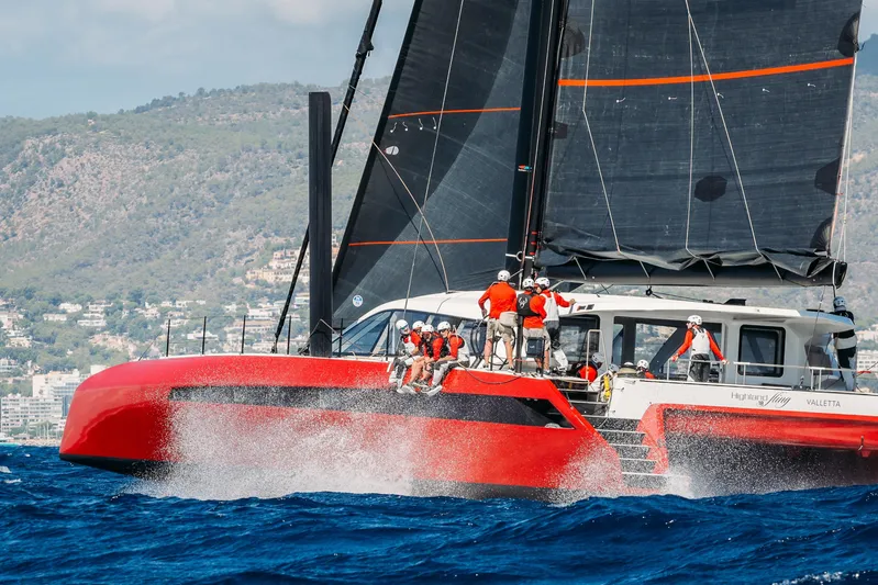 Highland Fling 18 Yacht Photos Pics 2023 Gunboat 80 sailing yacht with crew, vibrant red hull, cutting through ocean waves.
