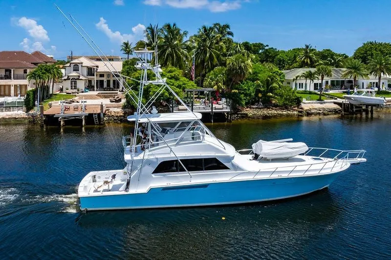 Energy Yacht Photos Pics 1998 Bertram Convertible yacht cruising near waterfront homes with palm trees.