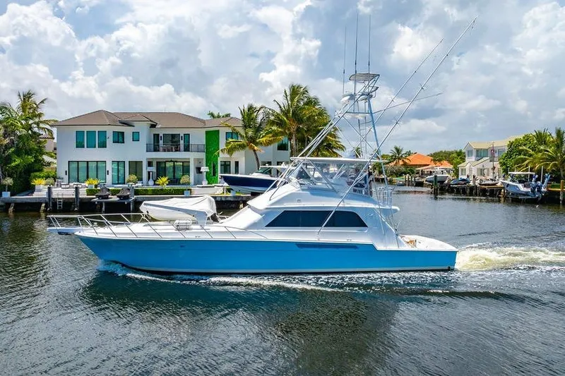 Energy Yacht Photos Pics 1998 Bertram Convertible yacht cruising near waterfront homes under a cloudy sky.