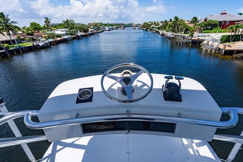 Energy Yacht Photos Pics 1998 Bertram Convertible yacht helm overlooking scenic canal with palm trees and blue sky.