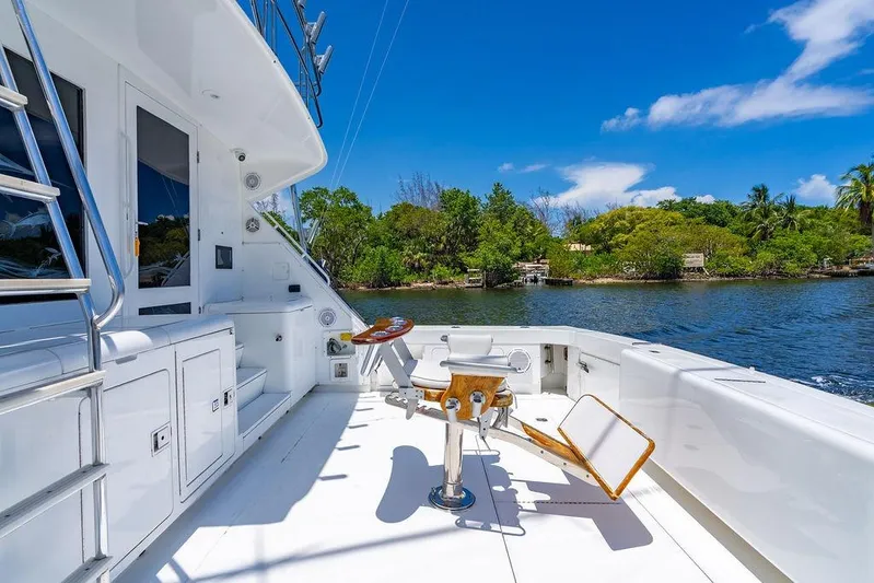 Energy Yacht Photos Pics 1998 Bertram Convertible yacht deck with fishing chair, surrounded by scenic water and lush greenery.
