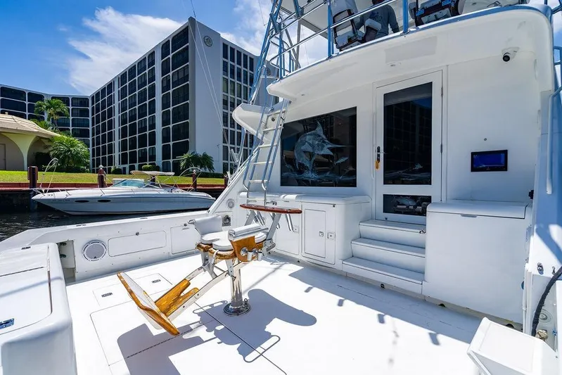 Energy Yacht Photos Pics 1998 Bertram Convertible yacht deck with fishing chair, docked near modern buildings.