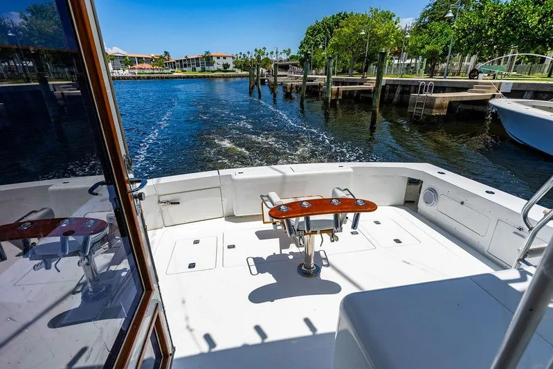 Energy Yacht Photos Pics 1998 Bertram Convertible boat deck with fishing chair, docked by a scenic waterfront.