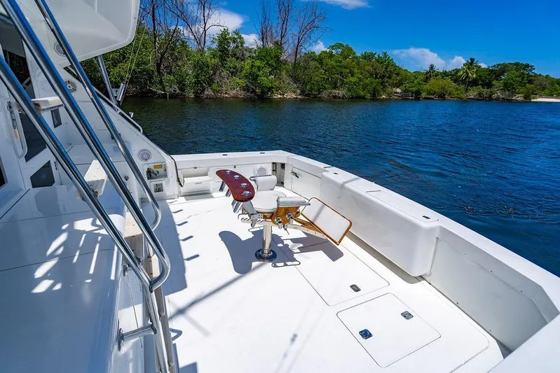 Energy Yacht Photos Pics 1998 Bertram Convertible yacht deck with fishing chair, overlooking serene water and lush greenery.