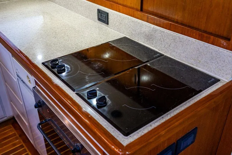 Energy Yacht Photos Pics 1998 Bertram Convertible yacht kitchen with sleek electric stovetop and wooden cabinetry.