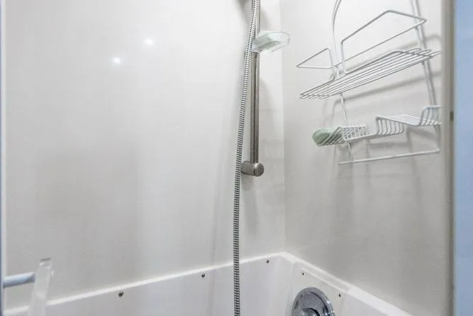 Energy Yacht Photos Pics Shower area in a 1998 Bertram Convertible boat with wall-mounted caddy and handheld showerhead.