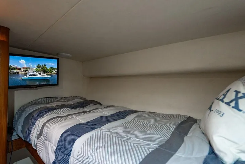 Energy Yacht Photos Pics Cozy cabin interior of 1998 Bertram Convertible with bed and TV showing a boat scene.