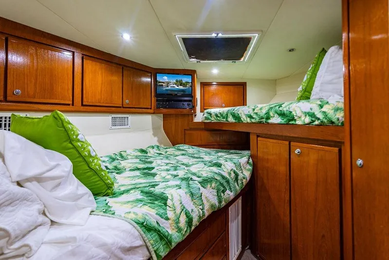 Energy Yacht Photos Pics 1998 Bertram Convertible cabin with wooden cabinets, twin beds, and tropical bedding.