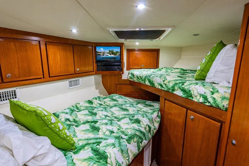 Energy Yacht Photos Pics Cozy cabin interior of 1998 Bertram Convertible with wooden cabinets and tropical bedding.