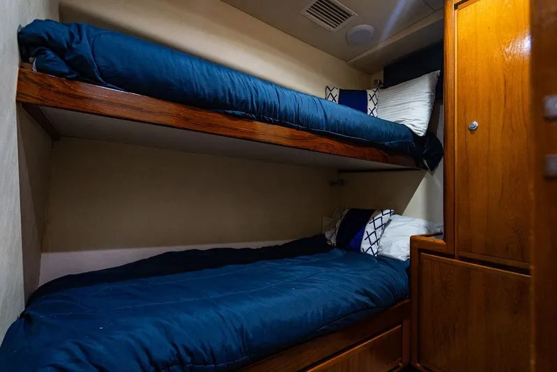 Energy Yacht Photos Pics 1998 Bertram Convertible yacht cabin with wooden bunk beds and blue bedding.