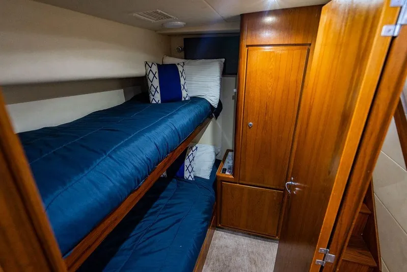 Energy Yacht Photos Pics 1998 Bertram Convertible cabin with wooden interior and blue bunk beds.