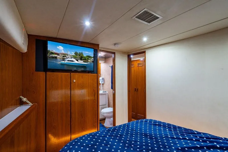 Energy Yacht Photos Pics Interior of a 1998 Bertram Convertible yacht cabin with wood paneling and a polka dot bedspread.