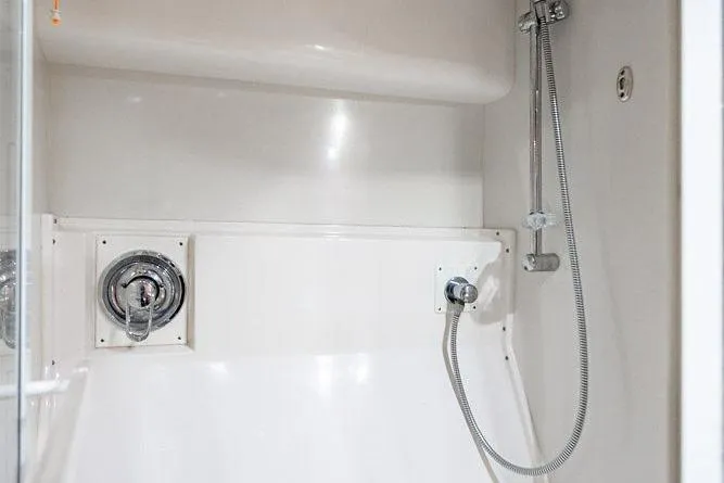 Energy Yacht Photos Pics Shower area in a 1998 Bertram Convertible boat, featuring chrome fixtures and white interior.
