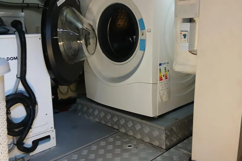  Yacht Photos Pics Laundry area inside 2022 Sirena 58 yacht, featuring a modern washing machine.