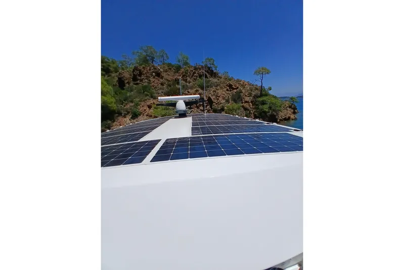  Yacht Photos Pics Sirena 58 yacht with solar panels, 2022 model, near rocky coastline under clear blue sky.