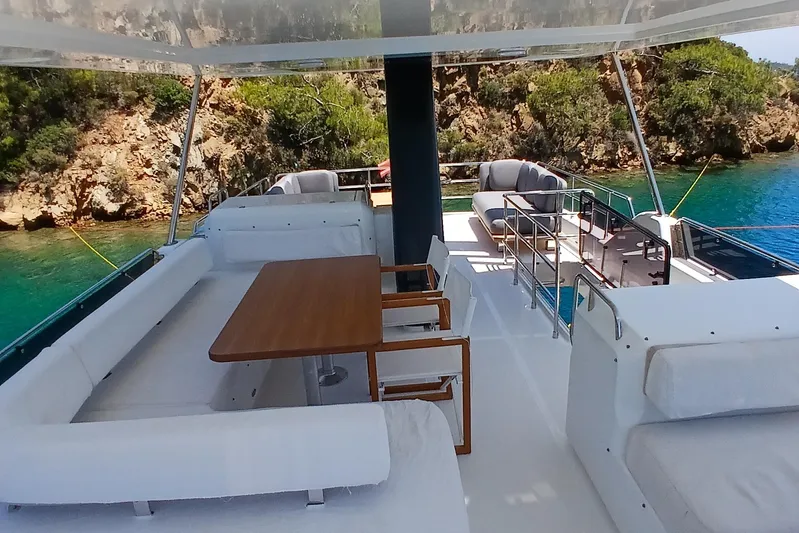  Yacht Photos Pics Luxurious 2022 Sirena 58 yacht deck with seating, table, and scenic coastal view.