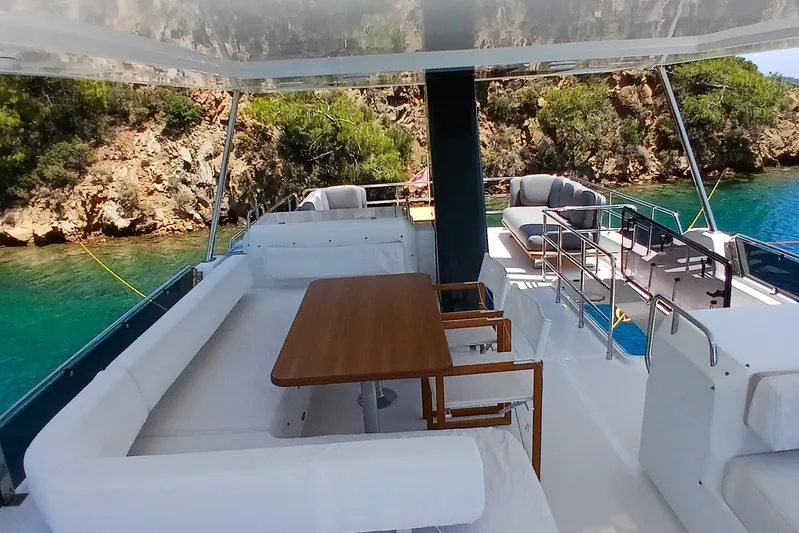  Yacht Photos Pics Luxurious 2022 Sirena 58 yacht deck with seating, table, and scenic coastal view.