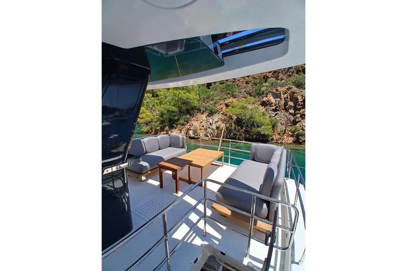  Yacht Photos Pics Luxurious Sirena 58 yacht deck with comfortable seating, overlooking scenic rocky shoreline.