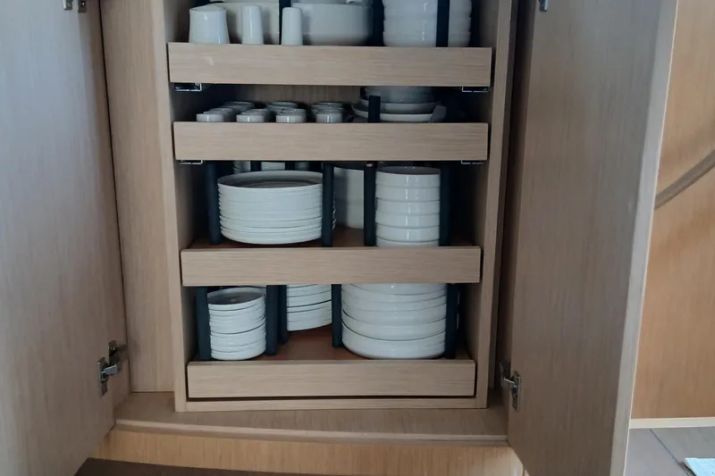  Yacht Photos Pics Wooden cabinet with organized white dishes and cups on pull-out shelves. Sirena 58, 2022 model.